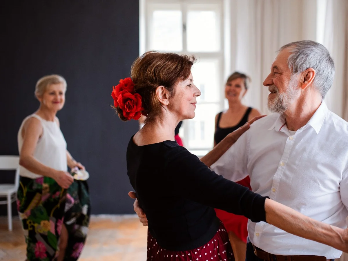 Senior Adults Dancing A group of smiling senior adults dancing in a bright, open studio with natural light.